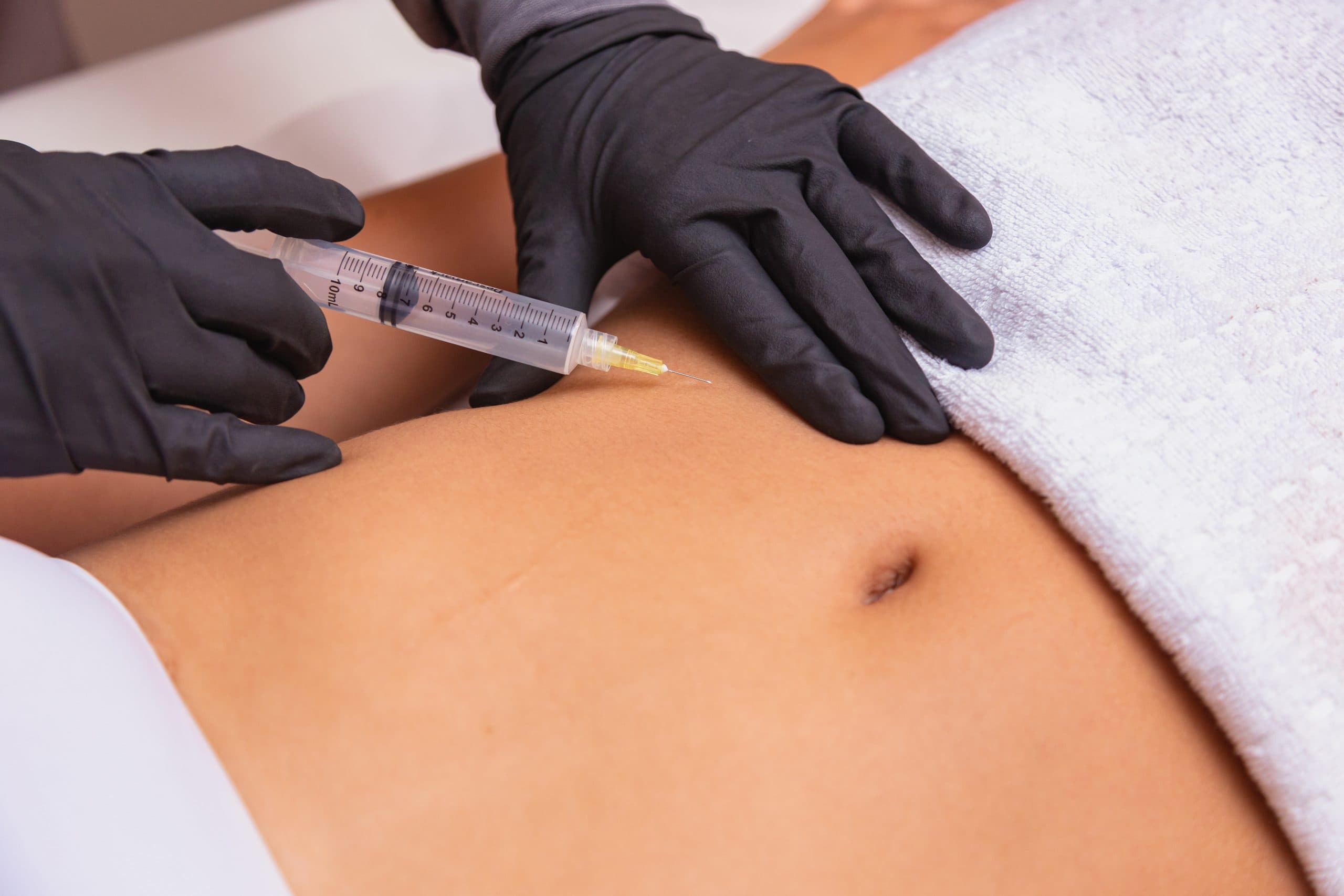 Close-up of abdomen injection with black gloves