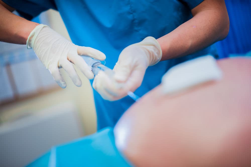 Gloved hands preparing injection material